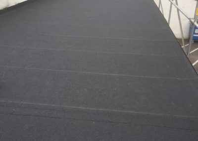 Finishing touches to the pergouet garage in Honiton after re-felting using a charcoal colour, high performance mineral